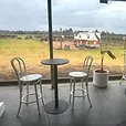 Black Atlas bar tables with white bentwood bar stools set up under cover at a vineyard event.