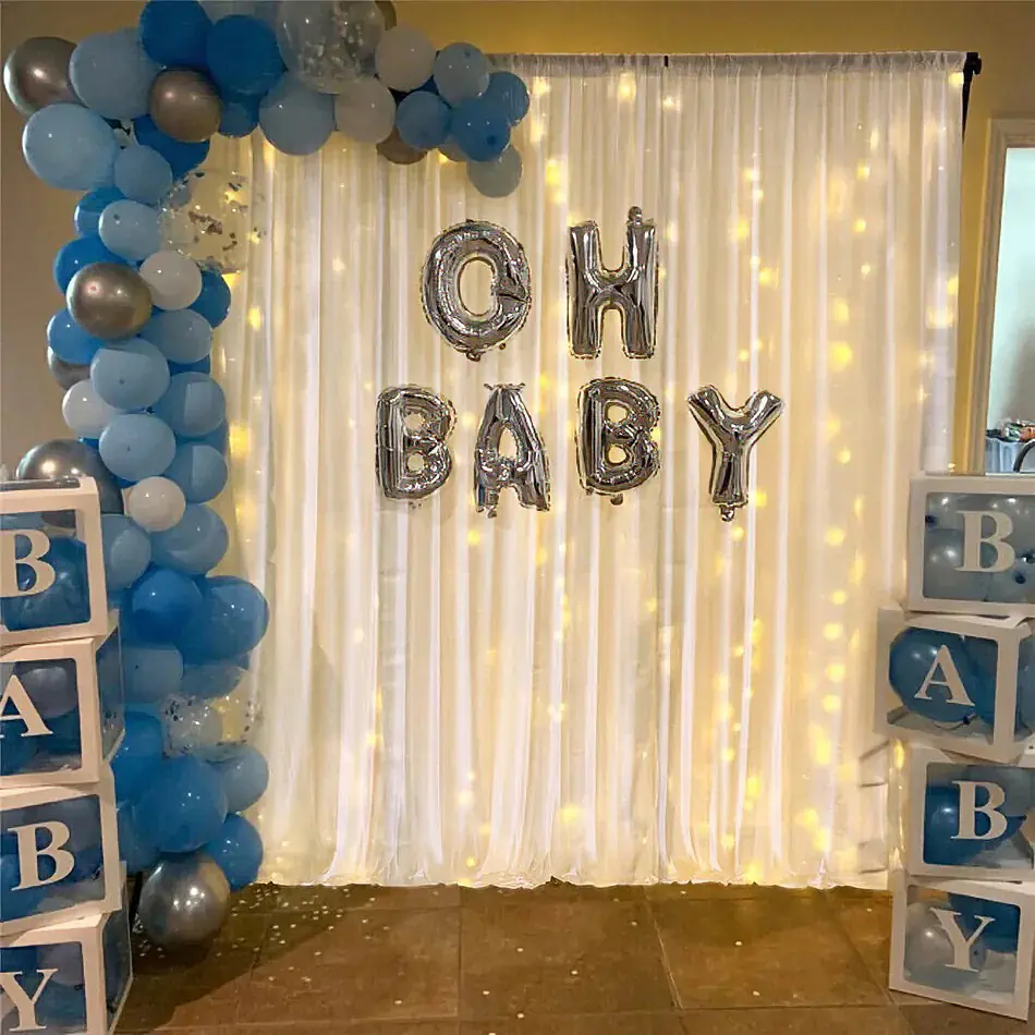 White draping with warm fairy lights, blue and silver balloon garland and baby shower balloon lettering for a styled celebration display