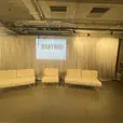 White draping behind white lounge seating, with a projected logo display and matching event furniture in an indoor venue