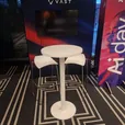 White exhibition stools arranged around a white Atlas bar table at an indoor event