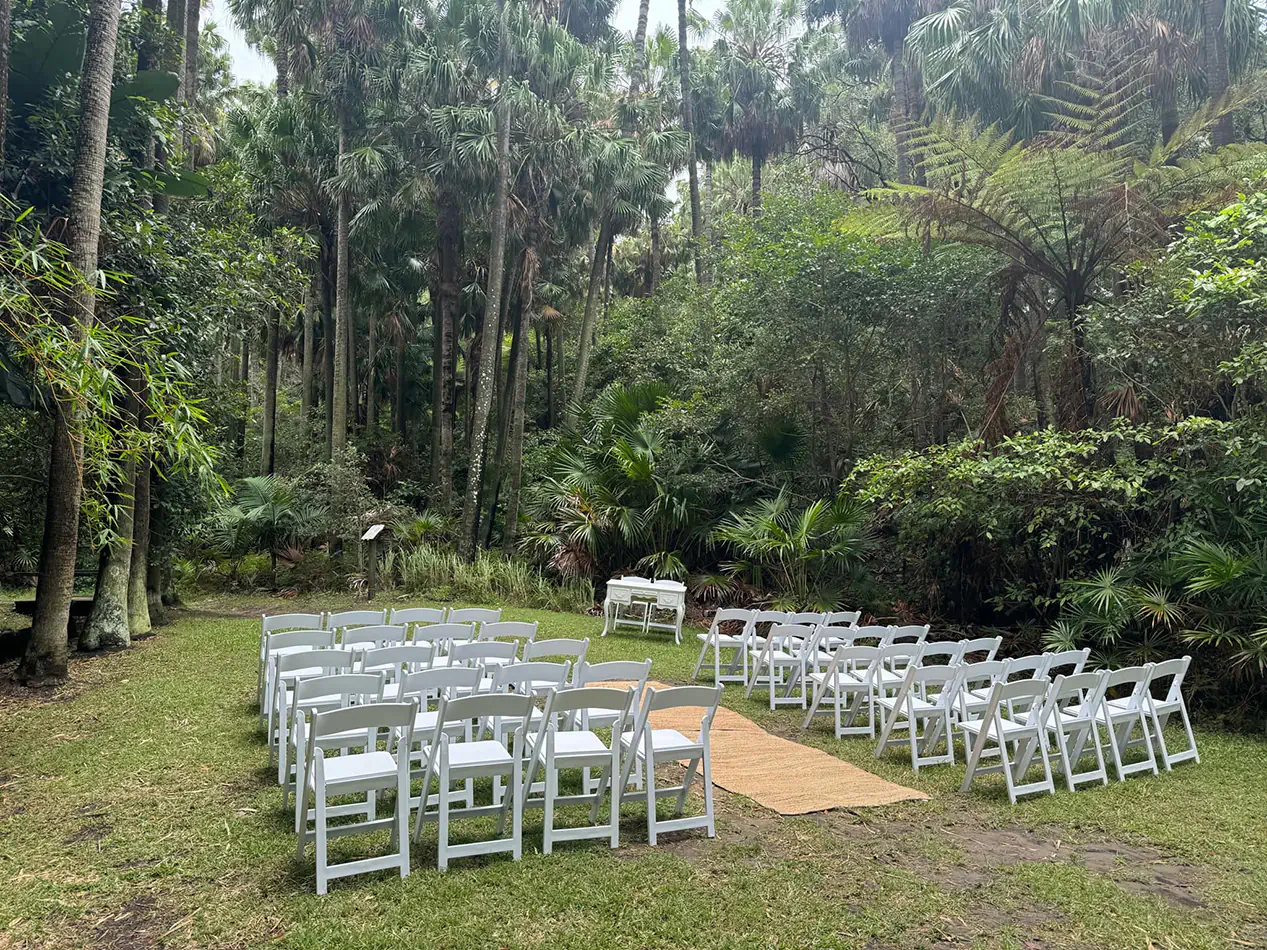 White folding chairs arranged in rows for an outdoor ceremony in a lush forest setting with greenery and natural surroundings