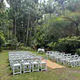 White folding chairs arranged in rows for an outdoor ceremony in a lush forest setting with greenery and natural surroundings