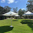 White market umbrella set up on grass in an outdoor garden space providing shade for an event area