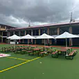 Multiple white market umbrellas providing shade over picnic tables in a school courtyard setting with open outdoor space