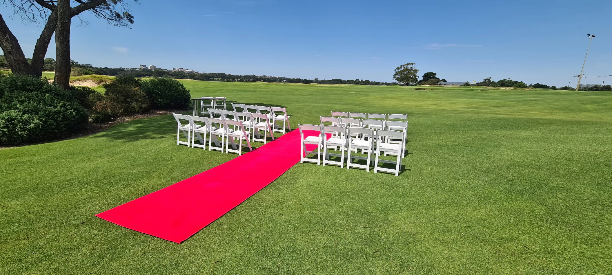 A wedding ceremony set up on a golf course with White Padded Folding Chair Hire.