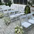 White padded folding chairs set up for a gladiator-themed wedding ceremony.