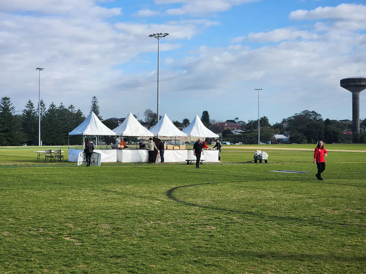 White peak marquees and event stalls set up on a sports field for an outdoor community event