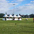 White peak marquees and event stalls set up on a sports field for an outdoor community event