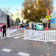 A street with a white picket fence and pink balloons.