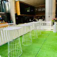 A white table and chairs set on a lush green grass lawn, creating a serene outdoor oasis within a building.