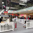A white picket fence enclosing a bustling shopping mall.