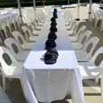 A table set up with white plastic stackable chairs and hats.