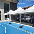 White pop-up marquees set up in a school courtyard for an outdoor event with shade coverage and tables underneath