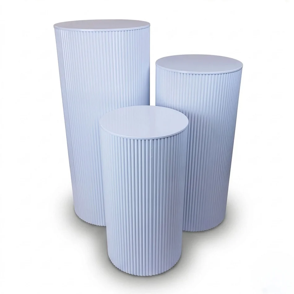 Three white ripple metal plinths with round tops and fluted sides in graduated heights