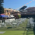 White round café tables with folding chairs arranged across a school lawn for an outdoor event
