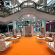 An orange carpet and white furniture, including a white round coffee table, in a mall.