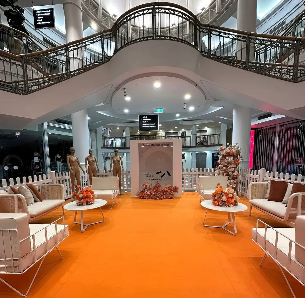 An orange carpet and white furniture, including a white round coffee table, in a mall.
