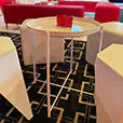 White round side table surrounded by white cube seating and lounge furniture inside a modern corporate event setup
