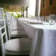 A table set up with white Tiffany chairs and white tablecloths.