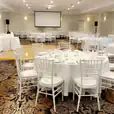 A large room with white tables and White Tiffany Chair Hire.