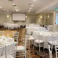 A large room with white tables and chairs available for White Tiffany Chair Hire.
