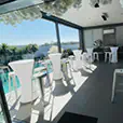 White Tolix stools paired with white cocktail tables on a bright covered balcony event area overlooking a swimming pool and outdoor view