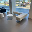 White velvet ottoman stools with quilted lounge seating and white wire coffee table inside a modern showroom lounge area