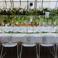 A white table with greenery and White Arrow Chair Hire.