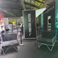 Two white wire arm chairs with black velvet cushions set up as a lounge area at an indoor fitness expo