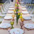 A long table set with colorful plates and glasses, featuring elegant White Wire Chairs.