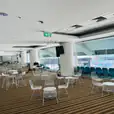 A large room with white wire chairs and tables arranged in the middle of a stadium.
