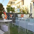 A white table and chairs in a garden, available for white wire cocktail table hire.