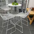 Three white metal chairs and a table on a patio. The patio furniture set includes three chairs and a white table, perfect for outdoor gatherings.