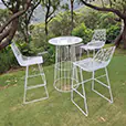 White wire cocktail table hire paired with matching seating set on a grassy outdoor garden location surrounded by trees and natural scenery