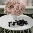 A white wire coffee table with a camera and a vase of roses.