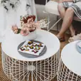 A white wire coffee table adorned with flowers, available for hire.