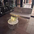 White wire lounge sofa with matching white wire coffee table, candles and floral styling arranged inside an elegant indoor event venue with timber flooring
