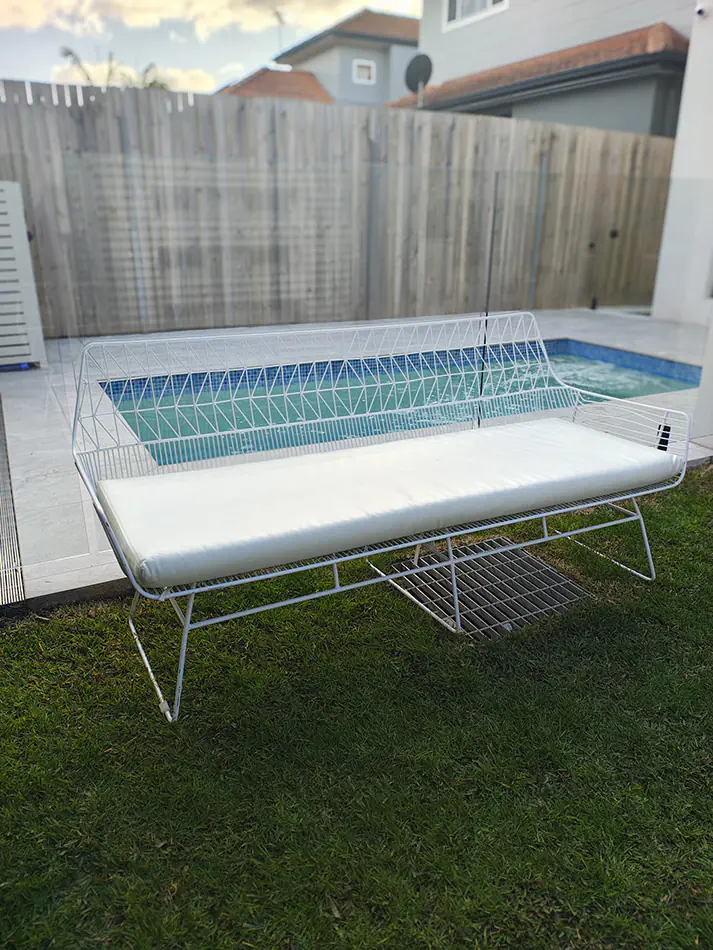 White wire lounge sofa with white cushions positioned in an outdoor waterfront event seating area