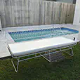 White wire lounge sofa with white cushions positioned in an outdoor waterfront event seating area