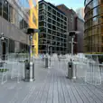 A white patio with chairs and tables in the middle of a city, featuring White Wire Stool seating options.