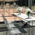 A table set up with white chairs and flowers, featuring a White Wire Stool Hire.