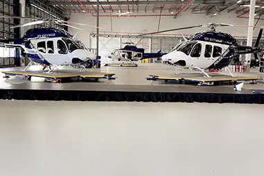 Large event stage platform in an aircraft hangar, positioned in front of police helicopters for a presentation or display event